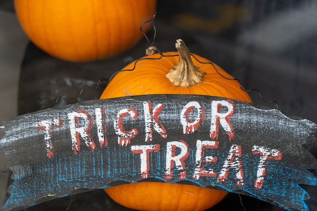 Orange pumpkins with a black sign and hand lettering reading "Trick or Treat"