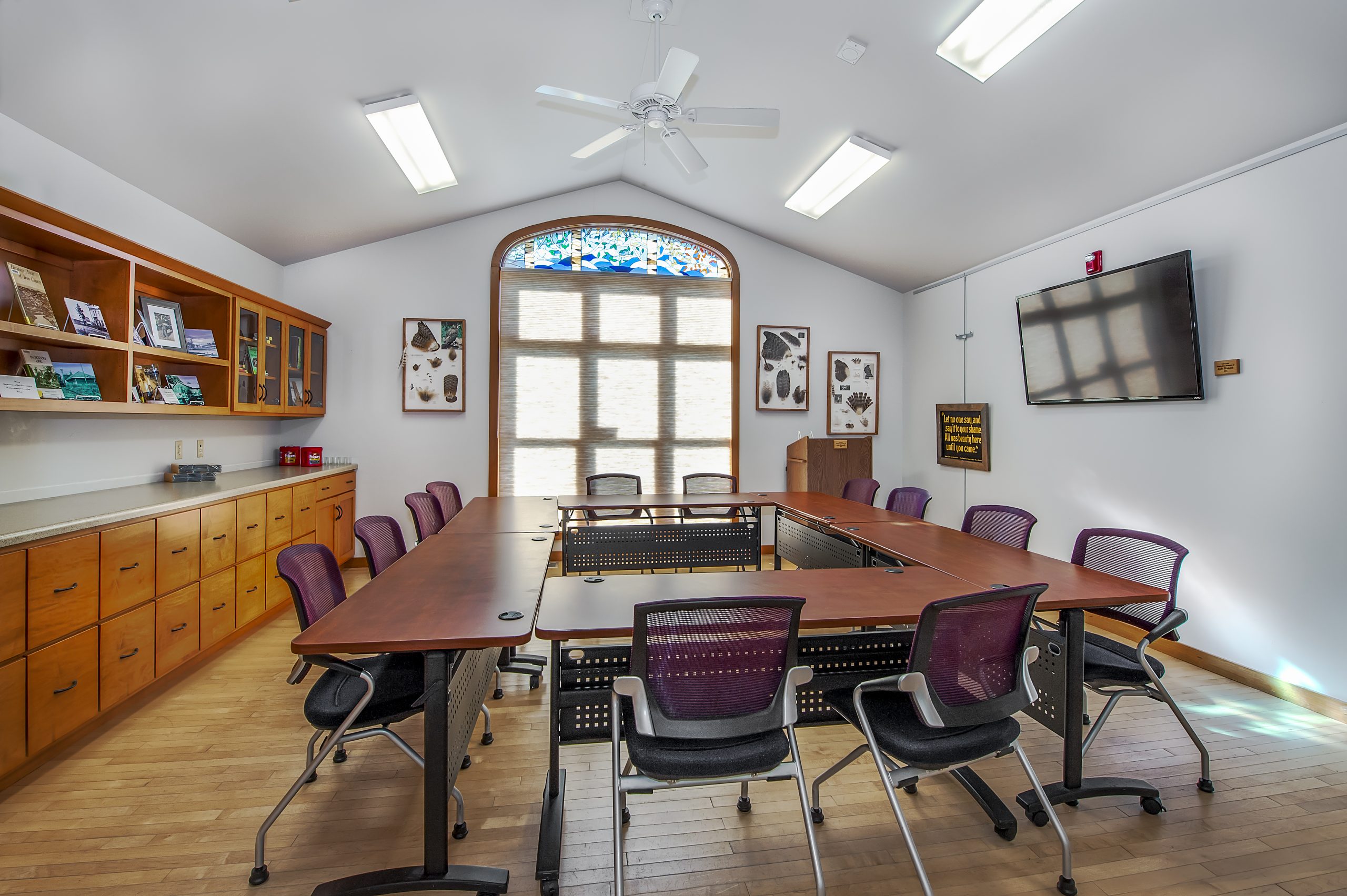 RCU Community Room. Large meeting room with window showing tables and chairs with a projector and retractable screen.